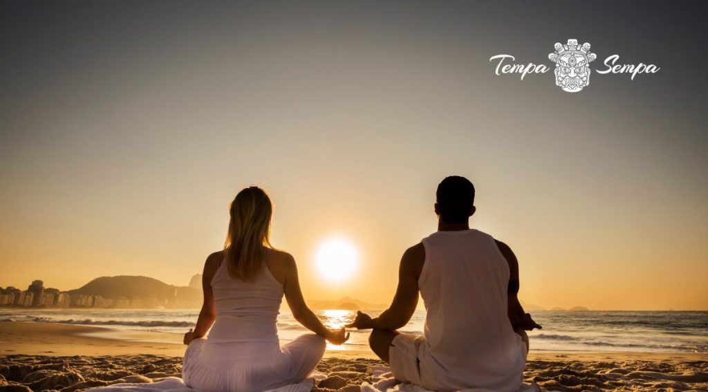 dos personas meditando al lado del mar